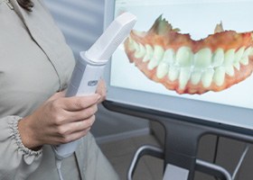 Hands holding dental device with digital dental imaging showing on screen