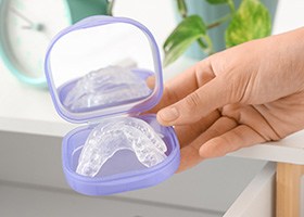 Hand placing nightguard in its case into bedside table drawer