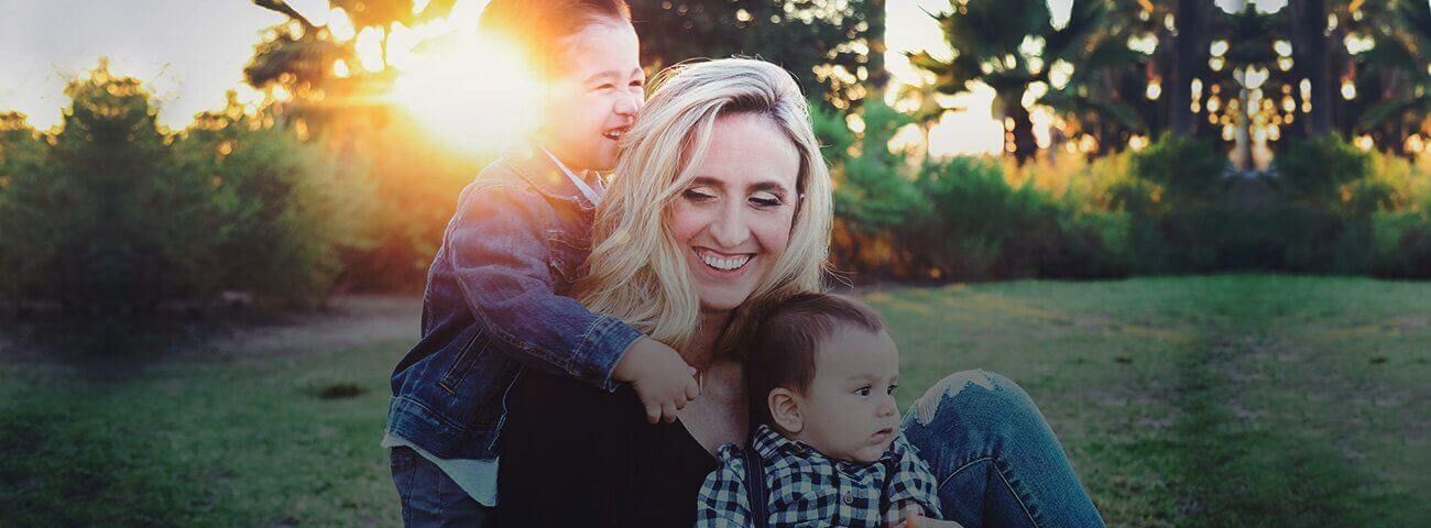 Mother and two sons laughing together outdoors