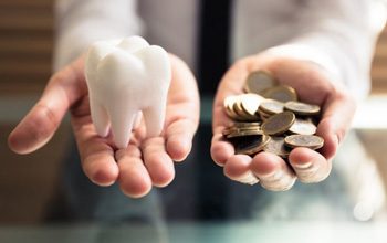 Person balancing a tooth and a pile of coins