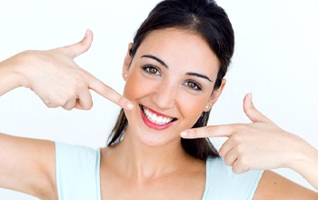 young woman pointing to her smile after getting direct bonding in Rochester 