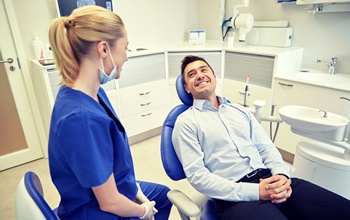 man sitting in dental chair and smiling at dentist