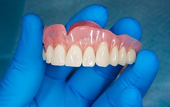 A closeup of a removable denture held in a gloved hand