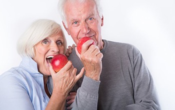 two people with dentures eating apples 