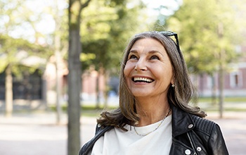 a person smiling and taking a walk in a park