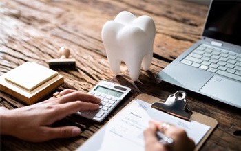 Patient calculating cost of care on desk with prop tooth