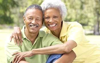 Couple smiling with implant dentures in Rochester