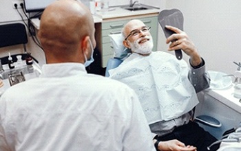 Man admiring implant dentures in Rochester