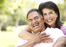 Smiling couple with dental implants in Rochester