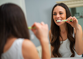 Young woman brushing her dental implants in Rochester