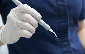 Close up of a dentist holding a soft tissue laser