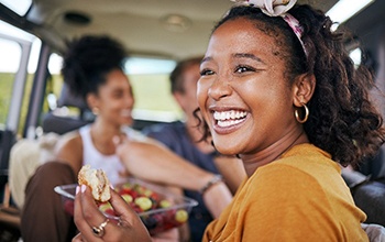 Woman smiling while eating healthy meal in the car with friends