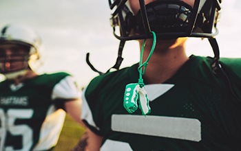 Closeup of green and white mouthguard hanging from helmet
