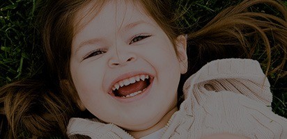 Little girl smiling while laying down on grass