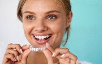 Woman smiling while holding teeth whitening tray