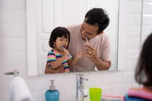 parent brushing their teeth next to their child