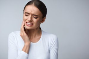 Woman in white shirt who needs emergency dentist in Rochester