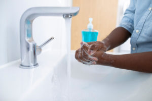 A dentist in Rochester disinfects their hands.