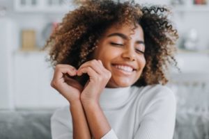 Woman smiling making a heart symbol with her hands