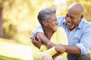 Smiling couple with dental implants in Rochester outside in summer