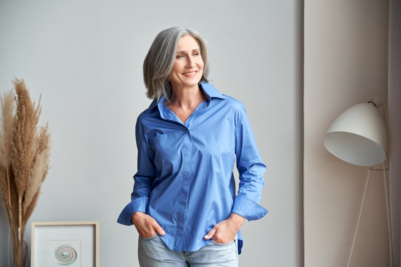 Smiling woman with dental implants standing inside