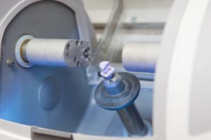 a crown being milled out of a block of porcelain in a CEREC machine