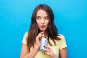 a woman smiling and drinking a beverage with a straw