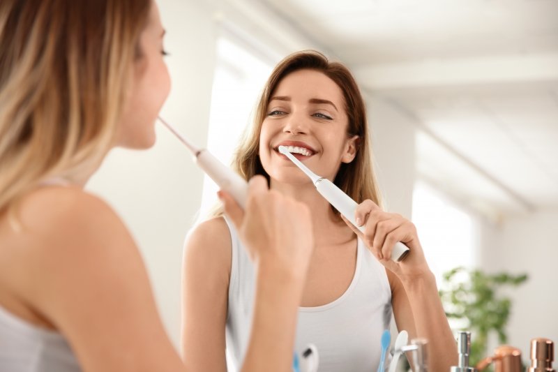 A woman brushing with an electric toothbrush