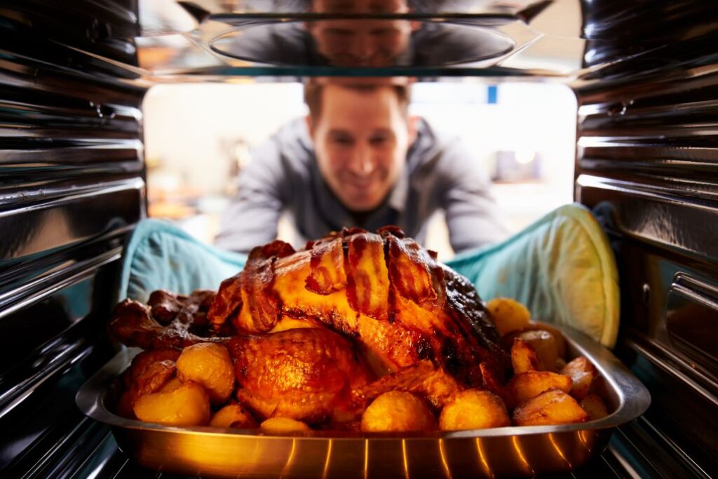 A man taking a turkey out of the oven