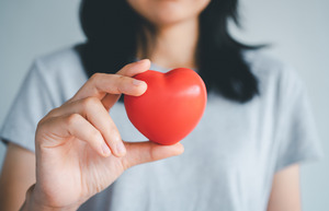Woman in grey shirt holding up a foam heart
